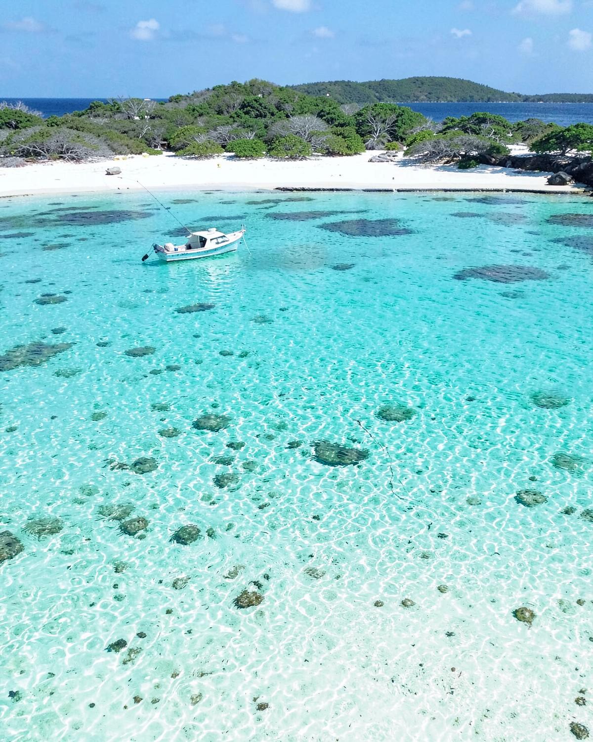 Turquoise Caribbean shallows with a boat anchored offshore