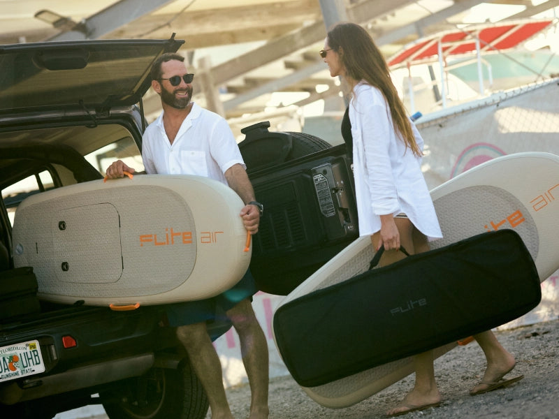 Couple loading Fliteboard AIR gear beside boats at the water's edge