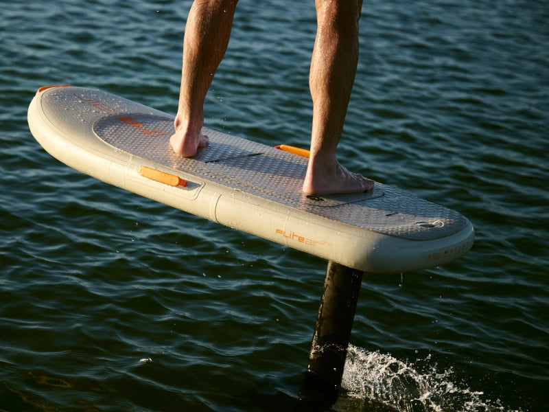 Close view of a rider's feet on a Fliteboard deck above the water