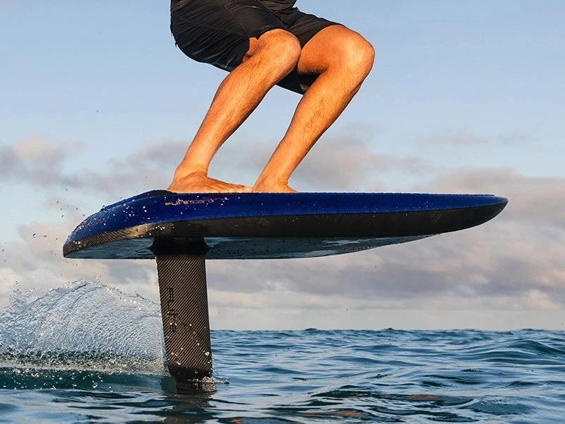 Rider carving on a blue eFoil above open blue water