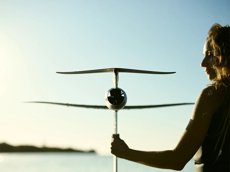 Rider holding a hydrofoil wing against a low sun