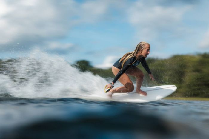 Blonde surfer riding a LIND electric surfboard on open water