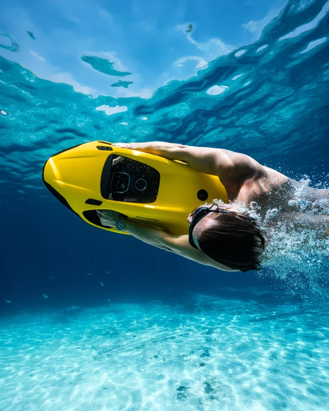 Rider gliding underwater behind a yellow SEABOB