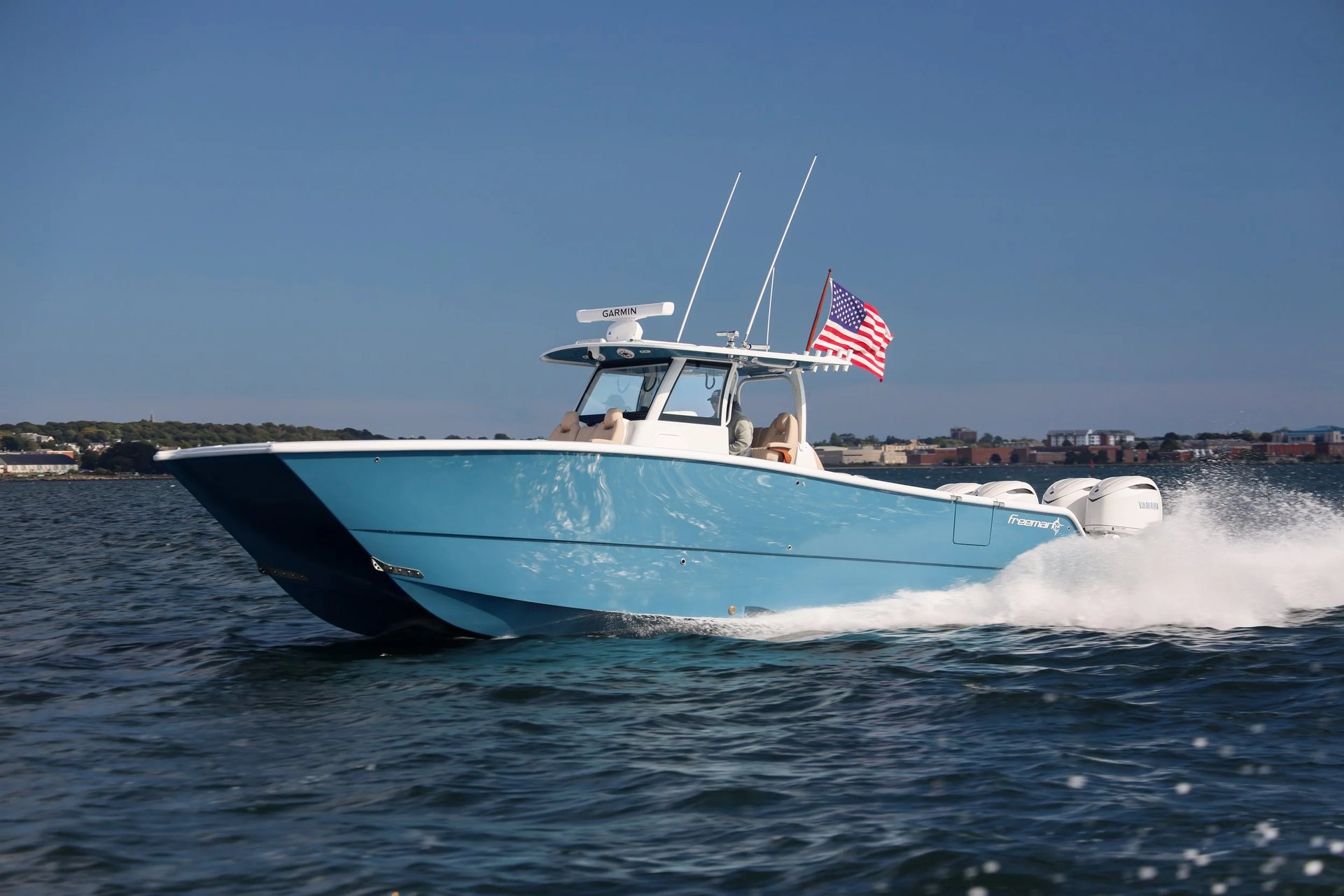 Profile of a Freeman center console catamaran under way with crew at the helm