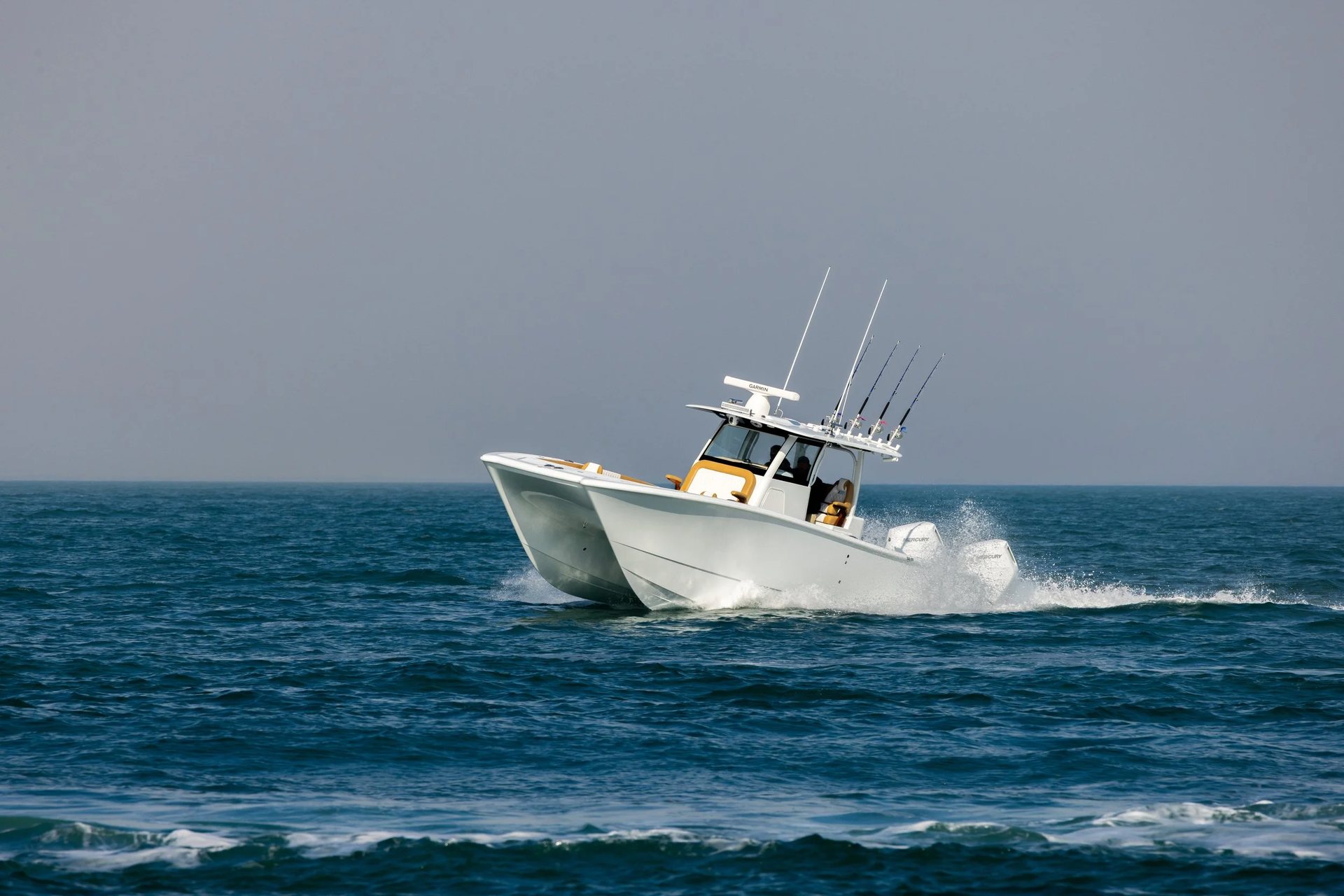 Offshore power catamaran with multiple outboards running fast across deep blue ocean