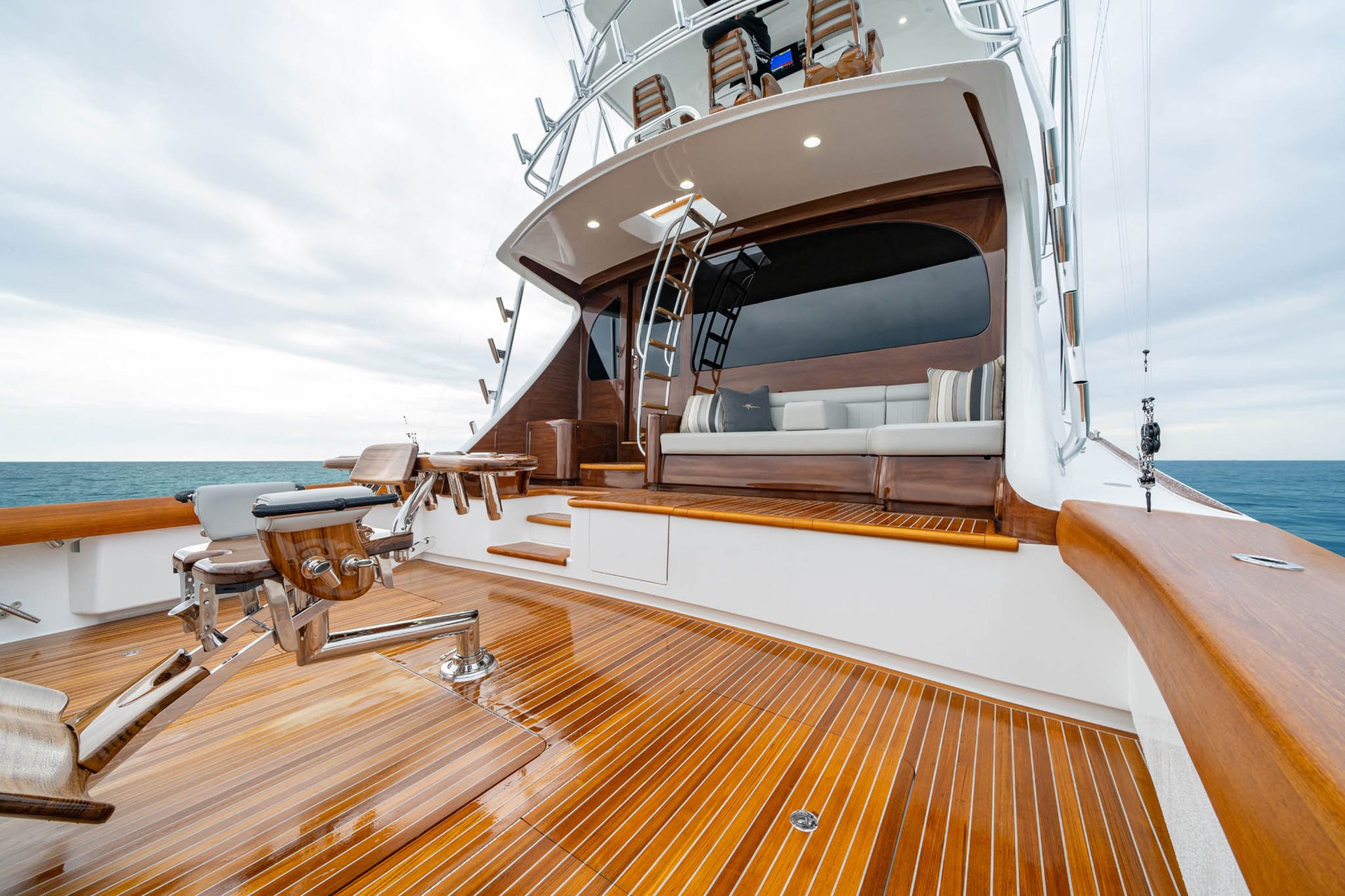 Crew working the cockpit of a sportfishing yacht with a bent rod offshore